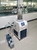Real laboratory setup of Geliss manifold stoppering vacuum freeze dryer connected to an external blue rotary vane vacuum pump.